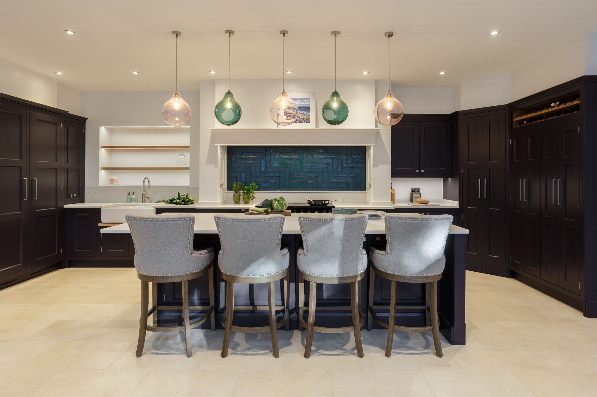 A kitchen showcasing a sleek and modern design with a large central island, above which a set of statement kitchen lights create a series of bright focal points that transforms the space. 